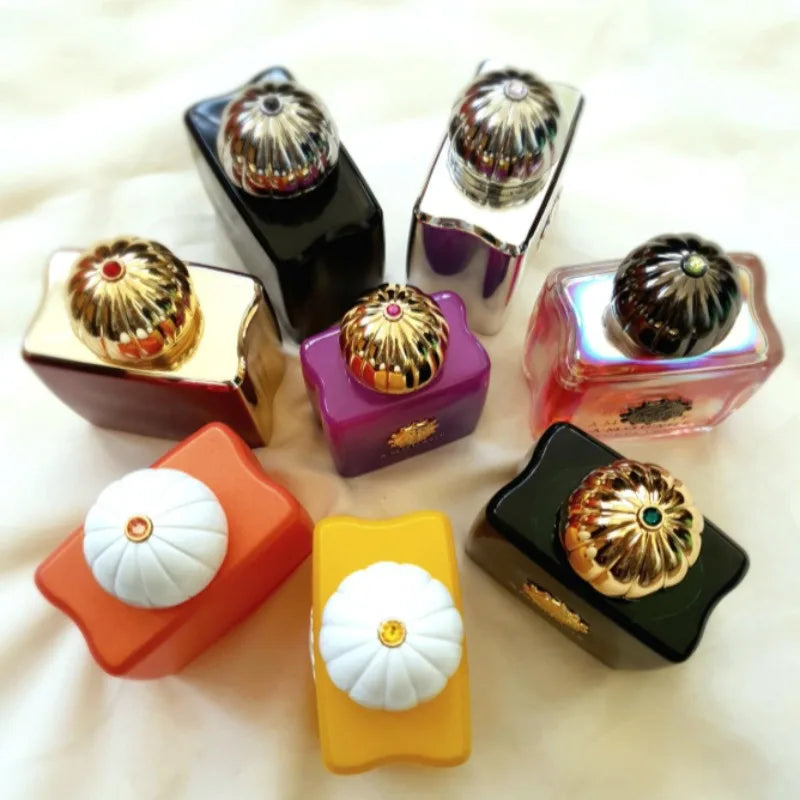 Collection of colorful luxury Amouage perfume bottles with gold domed caps arranged on a light background.