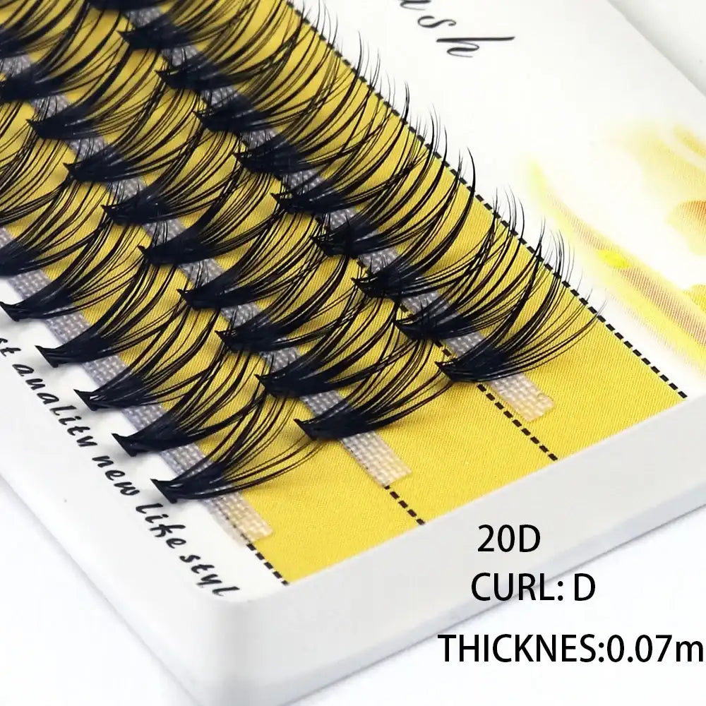Black 20D mink cluster eyelash extensions on a yellow tray, featuring a D-curl style for a voluminous look.