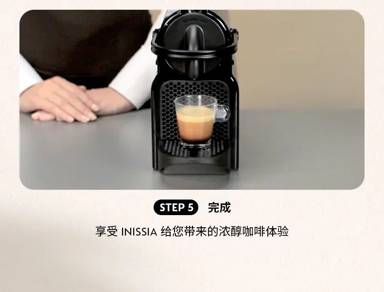 Black Nespresso Inissia coffee machine brewing espresso into a small glass cup on a modern kitchen counter.