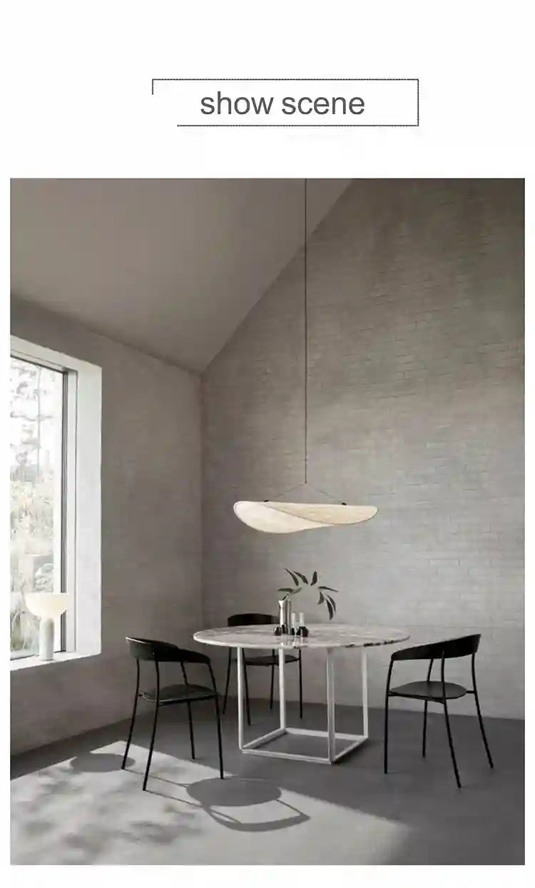 Off-white, wave-shaped pendant light suspended above a round dining table in a modern living space.