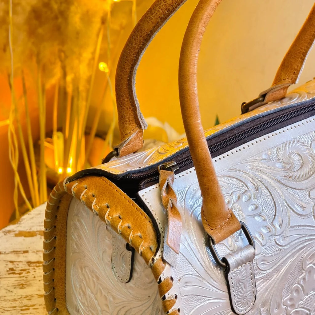 White floral tooled leather mini speedy duffel bag with tan leather handles, whipstitch trim, and zipper closure.