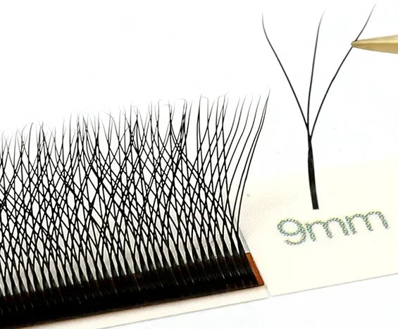 Black 3D W-shaped lash extension cluster being held by tweezers, with a strip of identical 9mm lashes on a tray.