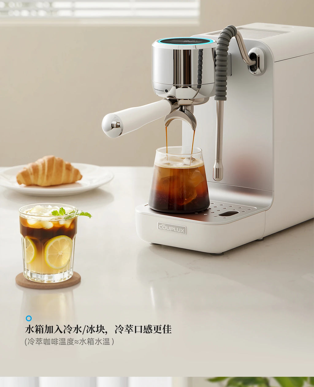 Couplux white compact espresso machine with silver accents brewing iced coffee into a glass on a modern kitchen counter.