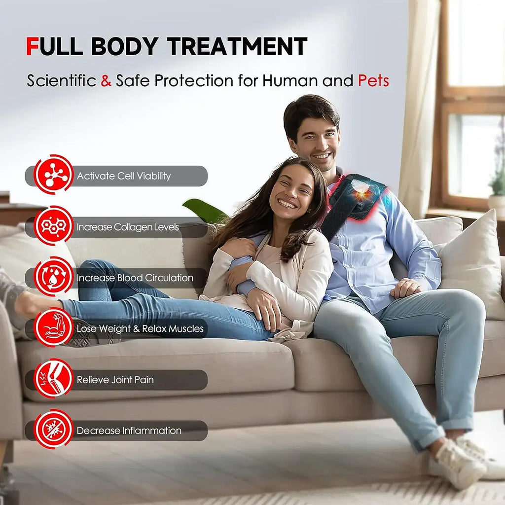 A man and woman sit on a sofa; the man wears a black red and infrared LED light therapy belt across his shoulder.