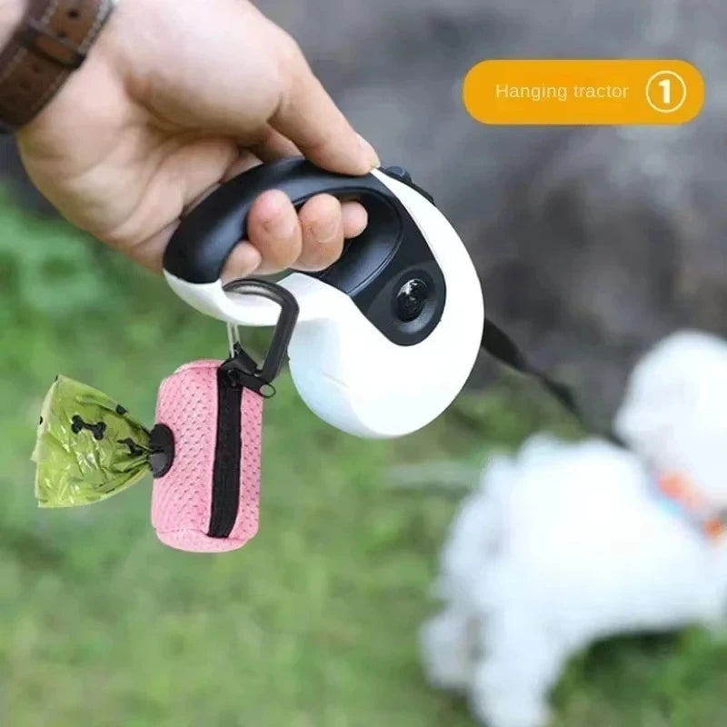 Pink mesh dog poop bag dispenser hanging from a retractable leash for easy waste pickup during pet walks.