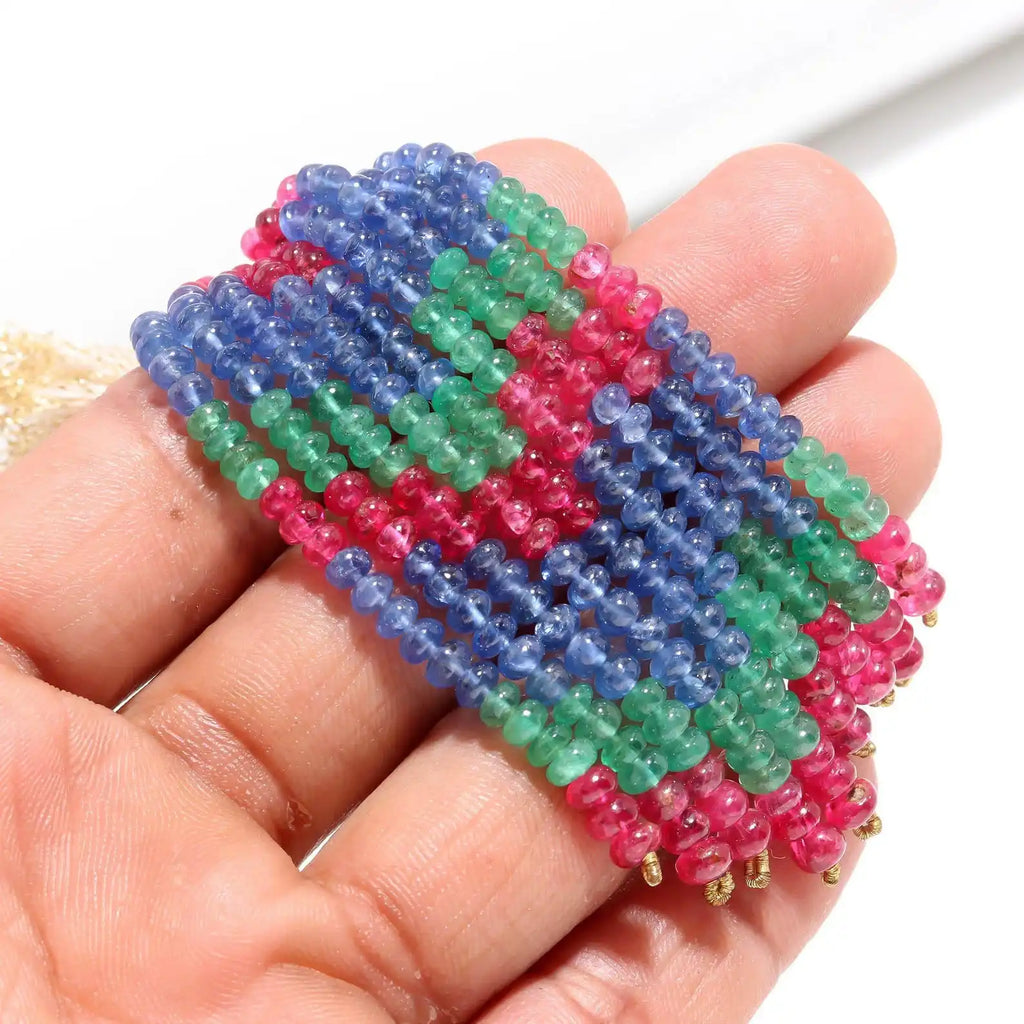 Close-up of 4mm smooth rondelle beads strand in blue, green, and pink on a hand.
