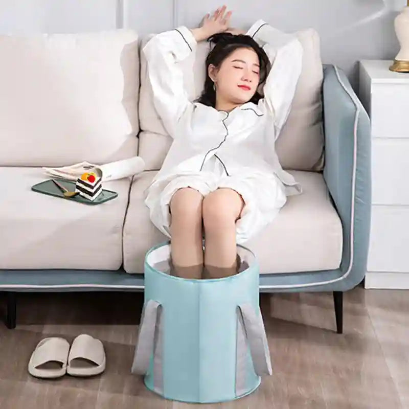 Woman relaxing on couch using a blue portable ionic foot detox spa bath massager for home therapy treatment.