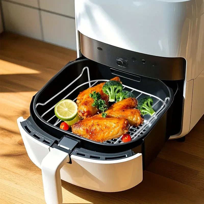 Air fryer steam rack with raised grid holding chicken, lemon slice, and greens