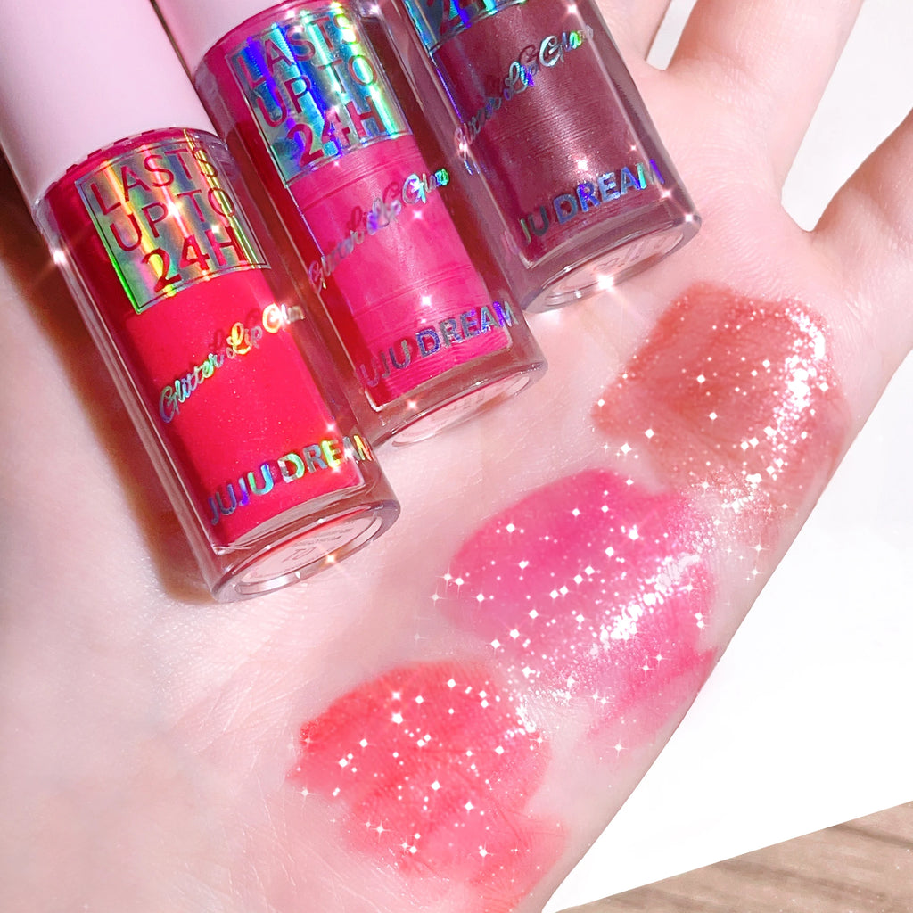 Three Juju Dream long-lasting waterproof glitter lip glosses with vibrant pink and berry swatches on hand.
