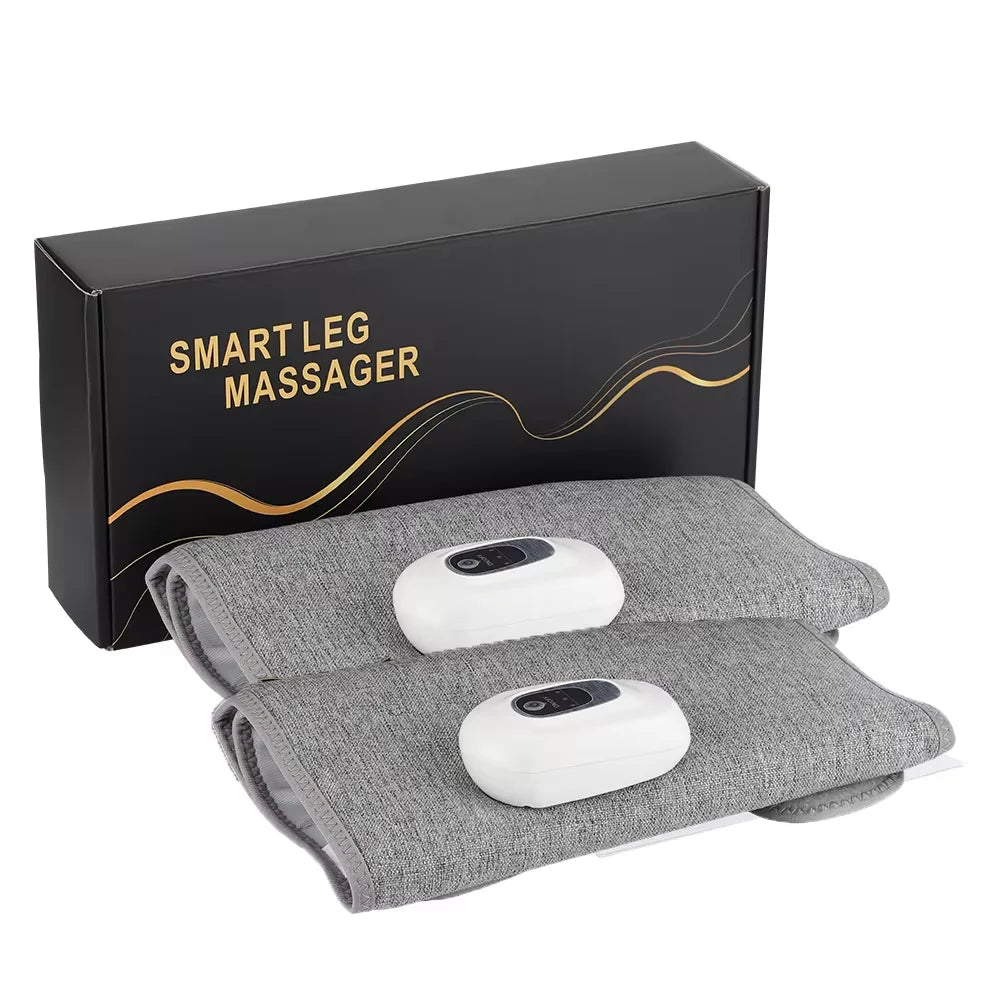 Two grey fabric leg massager wraps with attached white electronic controls, displayed in front of their storage box.