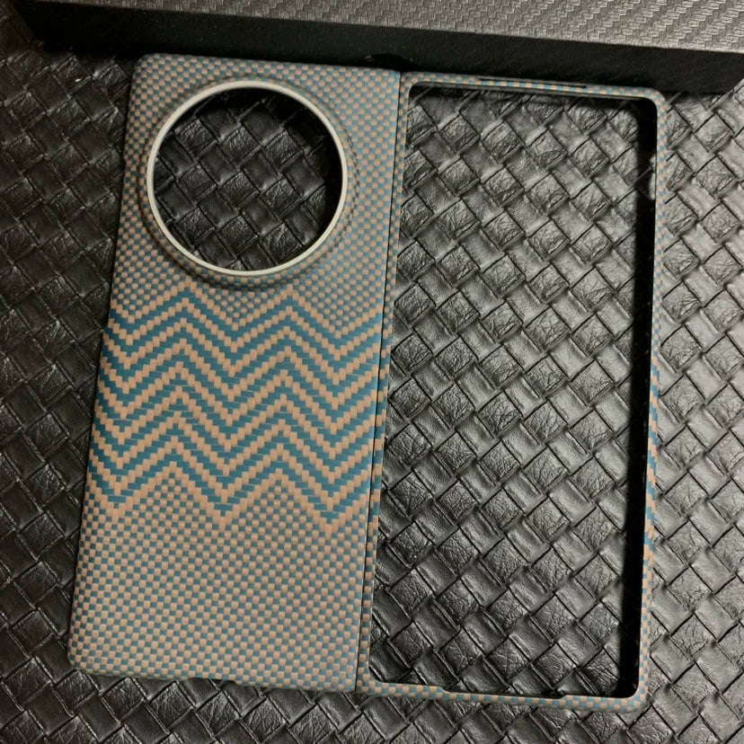 Carbon fiber phone case with blue and beige zigzag pattern and large circular camera cutout for protection.