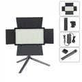 Rectangular LED video light with black barn doors on a mini tripod, including remote control, power adapter, and mount.