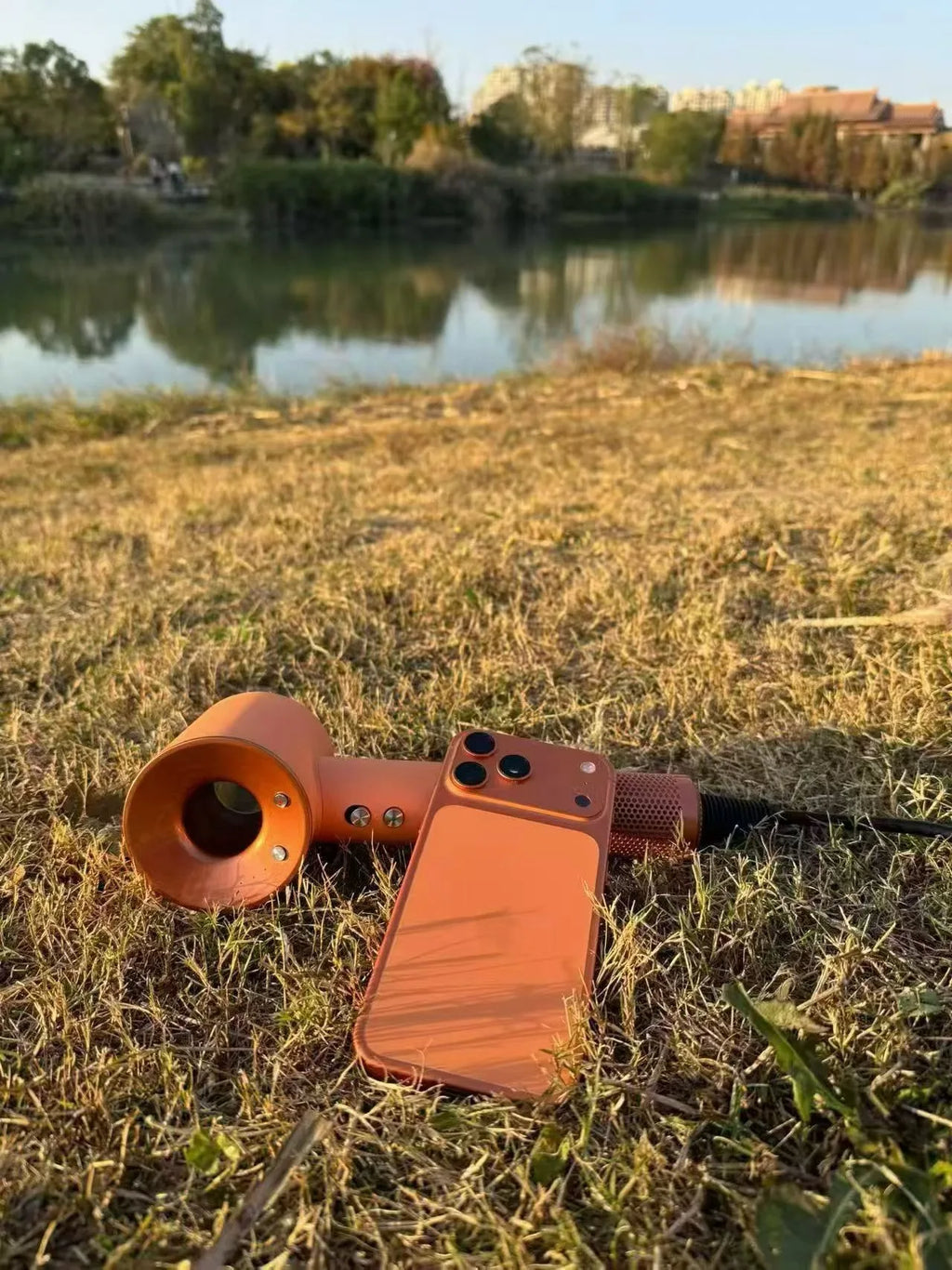 Orange high-speed bladeless negative ion hair dryer with magnetic attachments, displayed outdoors on grassy terrain.