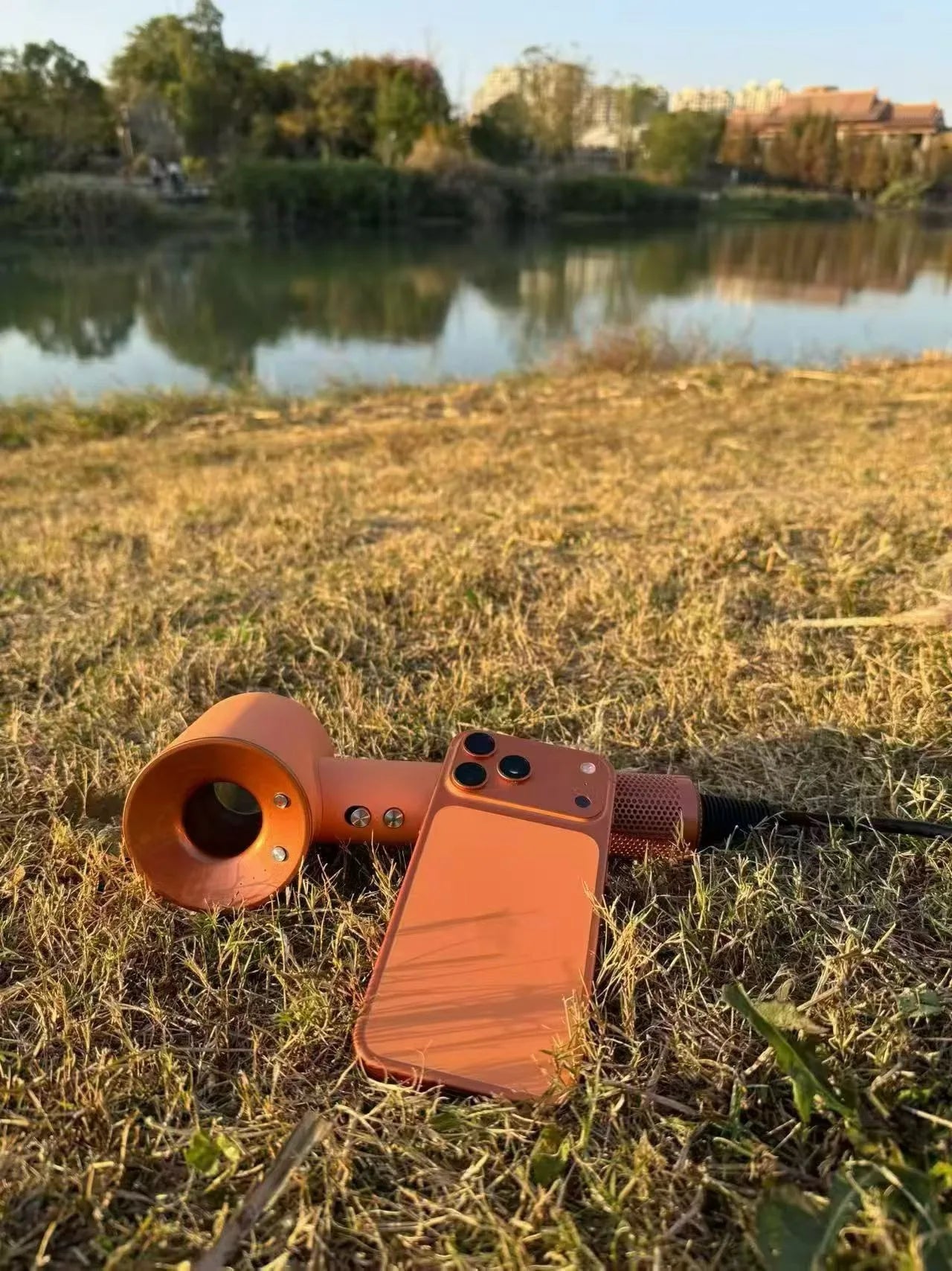 Orange high-speed bladeless negative ion hair dryer with magnetic attachments, displayed outdoors on grassy terrain.