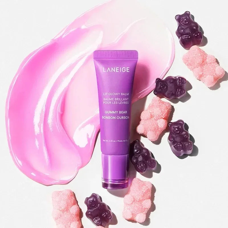 Laneige Gummy Bear Lip Glowy Balm in a purple tube with a glossy pink swatch and gummy bear candies on white background.