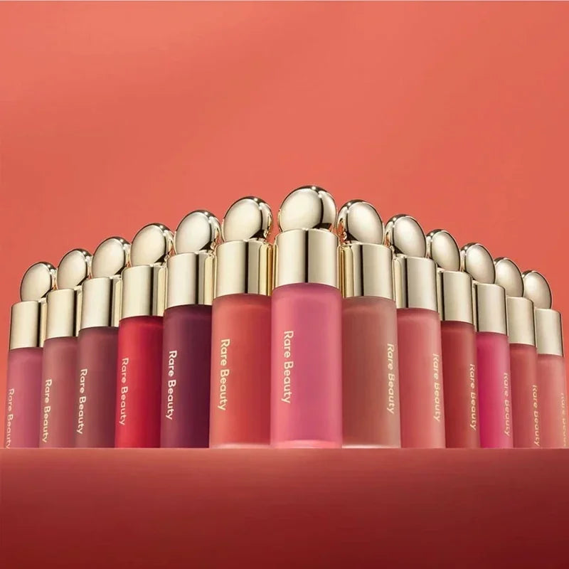 Rare Beauty matte lipstick collection in diverse rich colors with a smooth, moisturizing finish in gold-capped bottles.