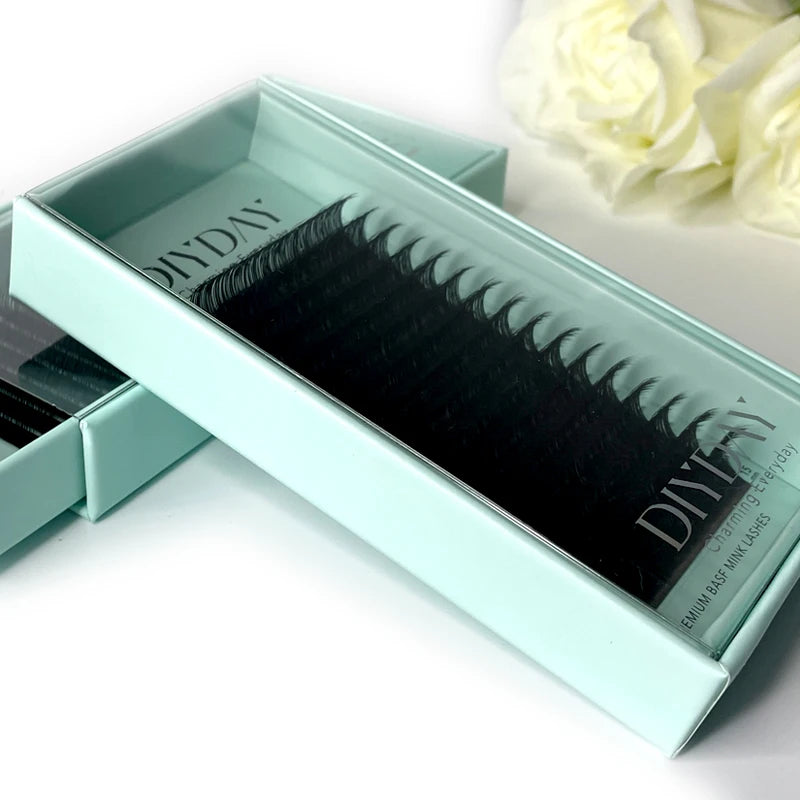 Tray of black mink individual eyelash extensions in a light mint green sliding box.