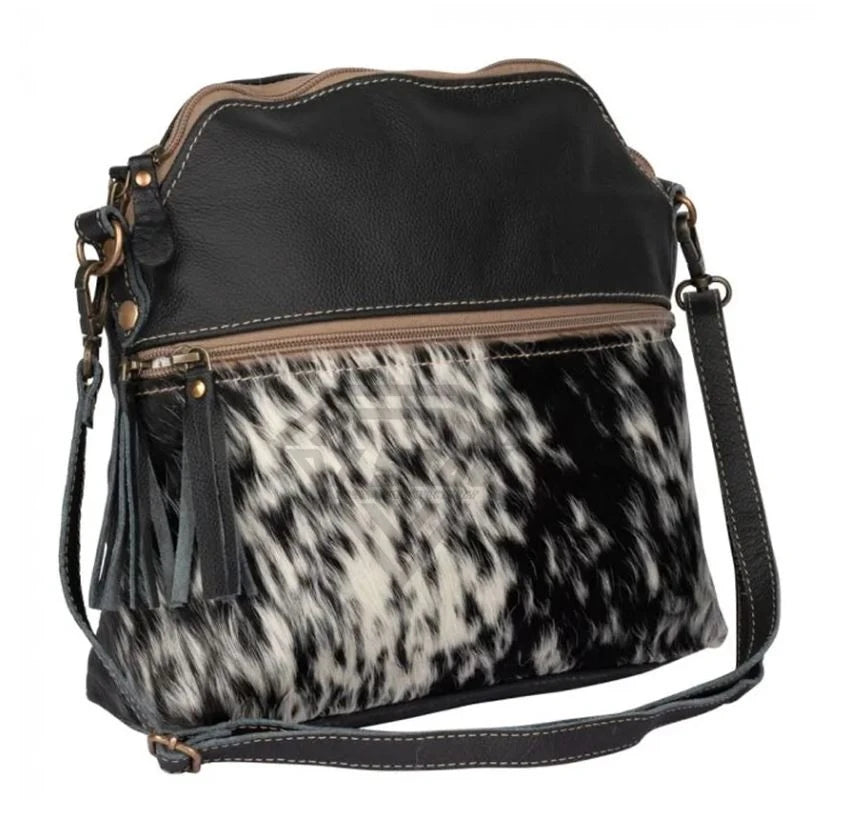 Luxury handmade designer crossbody bag in black leather and cowhide hair-on-hide with tassel detail.
