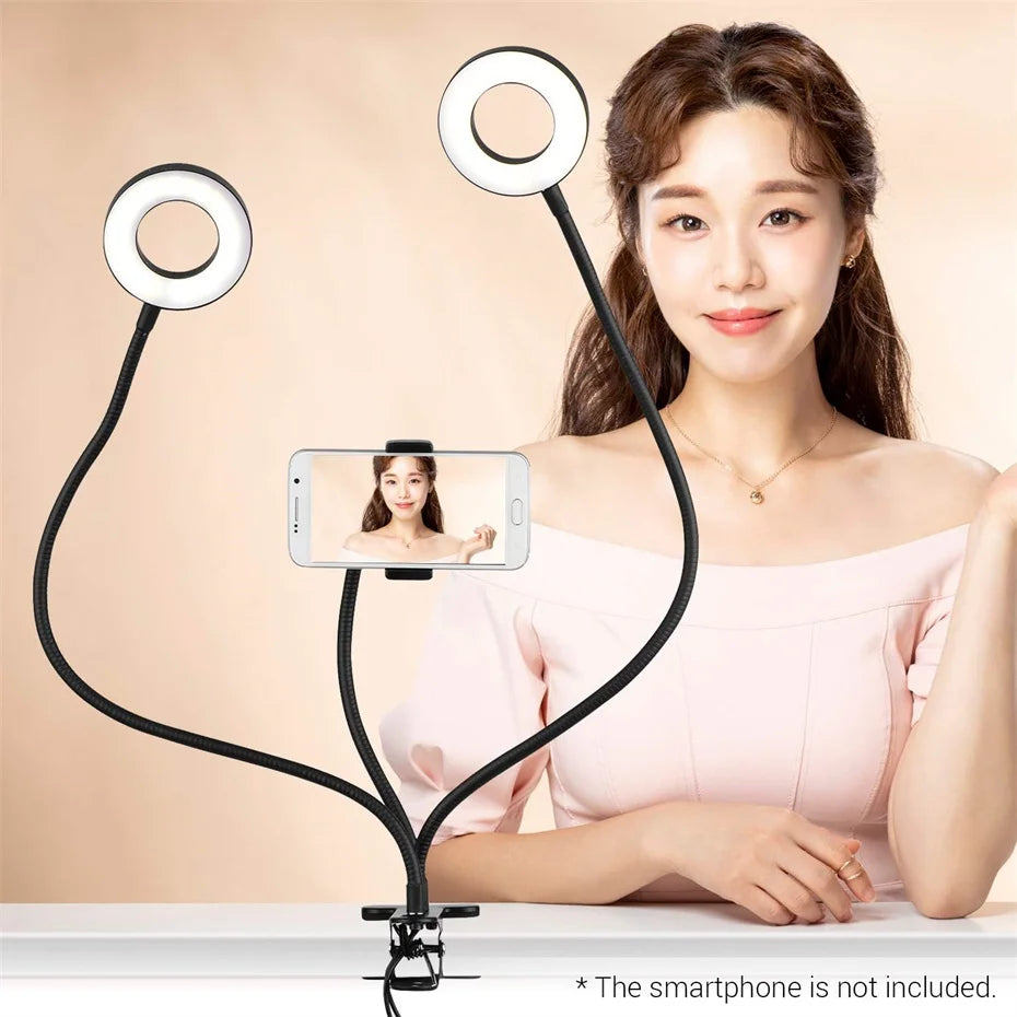 Dual-ring LED light with flexible gooseneck arms and a central smartphone clamp for video recording and streaming.