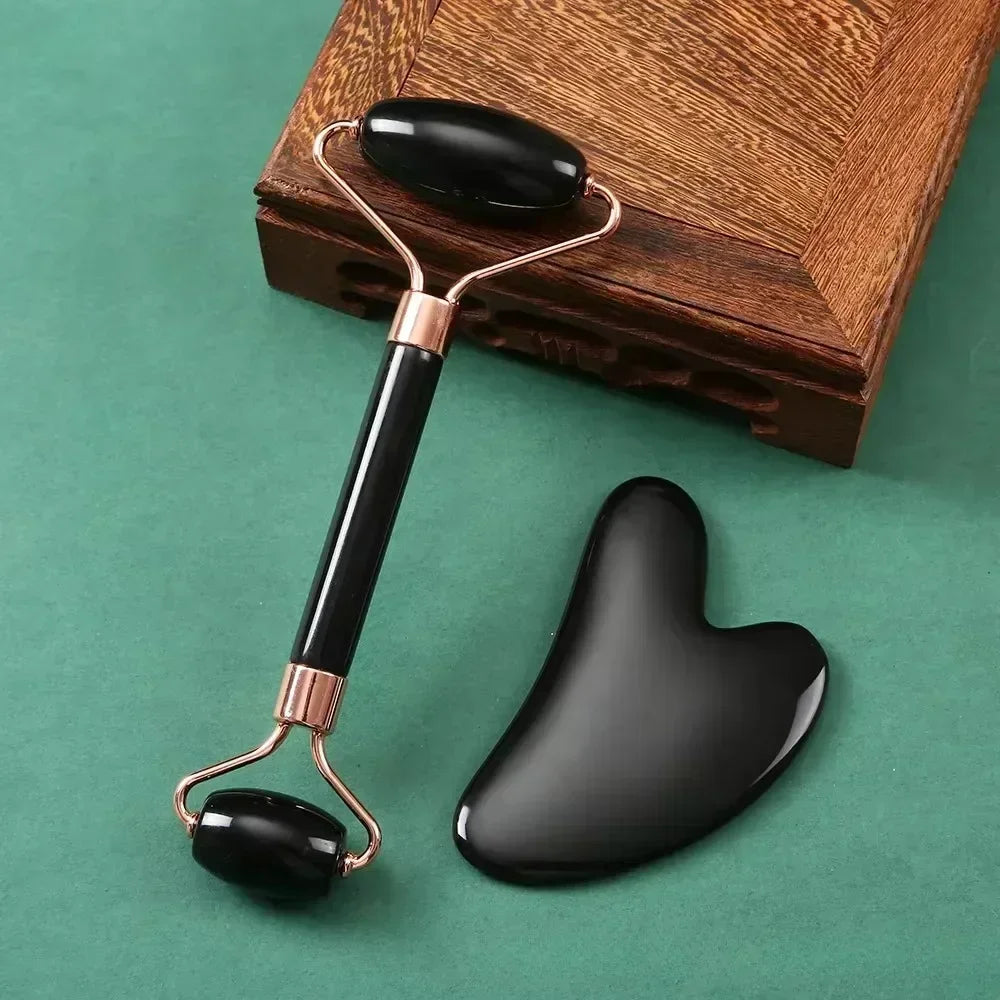 Black resin facial roller and heart-shaped Gua Sha scraper set for anti-aging skin massage and face lifting.