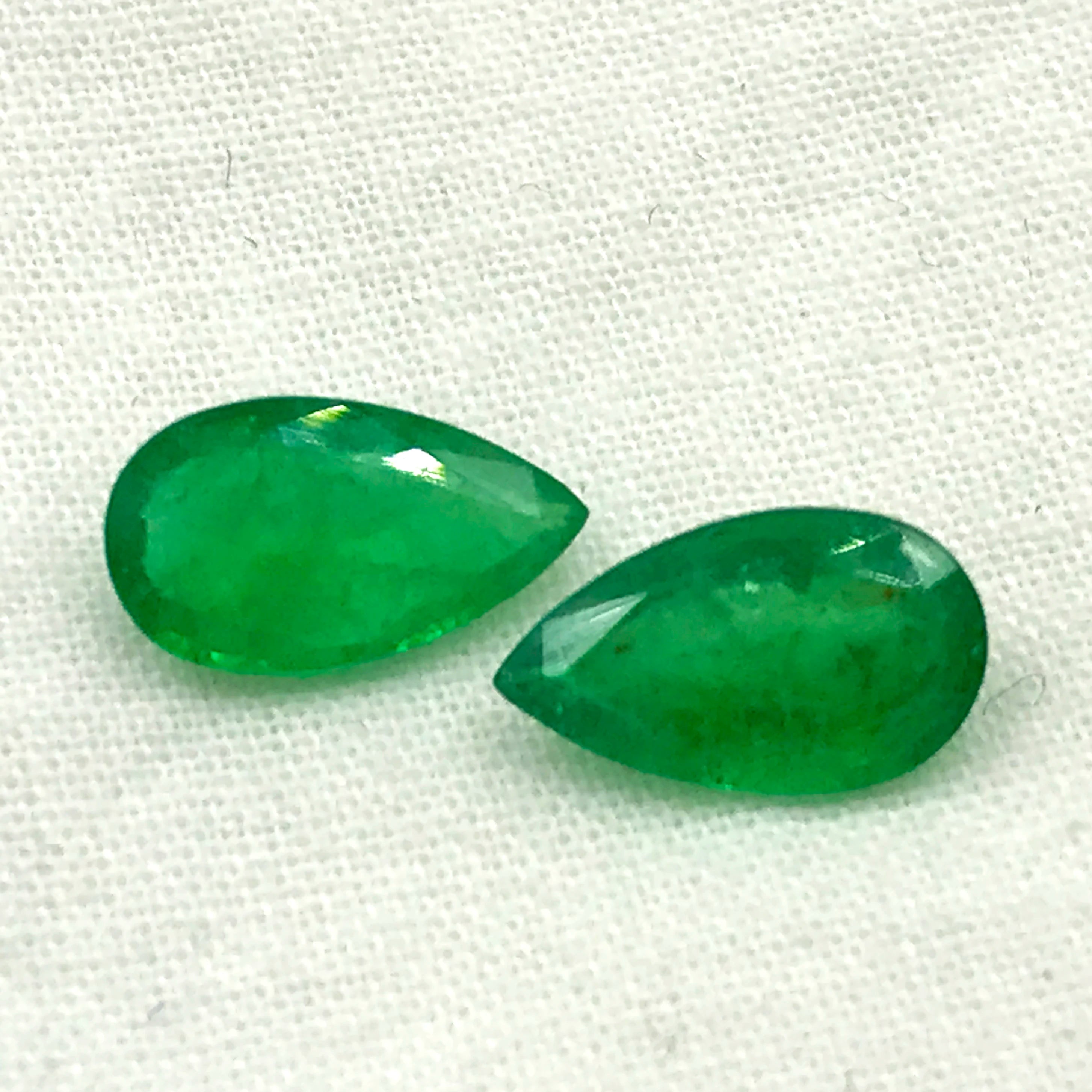 Two green oval-teardrop gemstone cabochons, smooth polished look