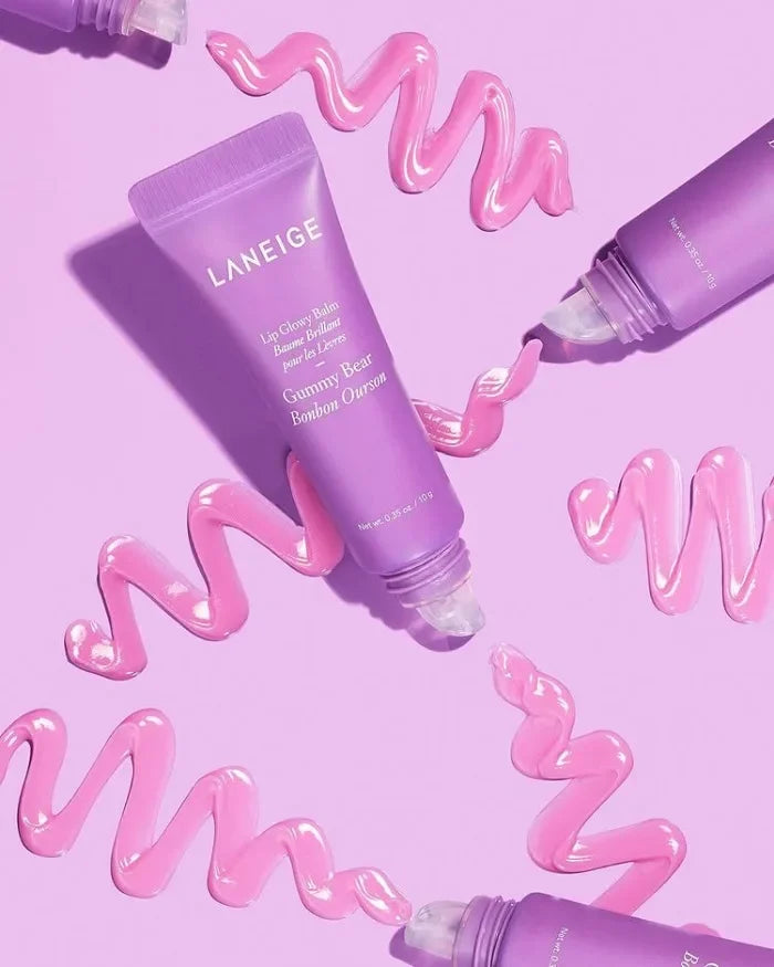 Laneige Gummy Bear Lip Glowy Balm tube with pink glossy hydrating lip moisturizer swatches on a purple background.