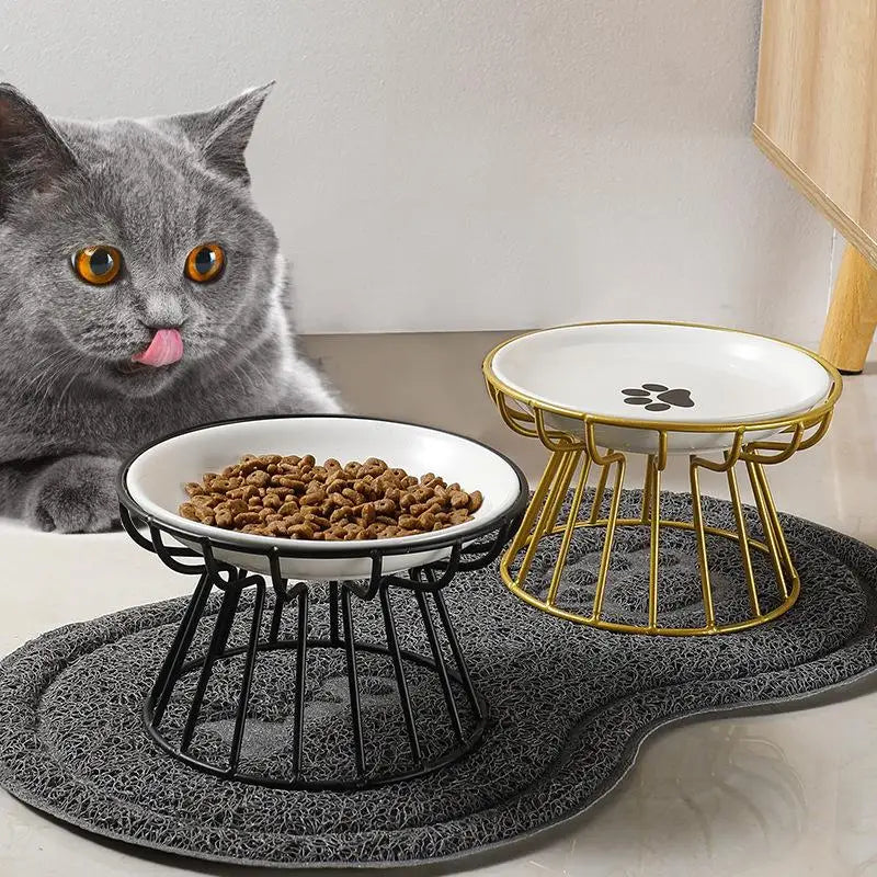 Gray cat eating from an elevated ceramic pet bowl with gold and black wire stand for comfortable, spill-free feeding.