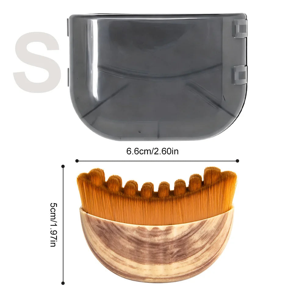 Small semicircular facial brush with wooden handle and thick orange bristles, shown with a dark gray protective cover.