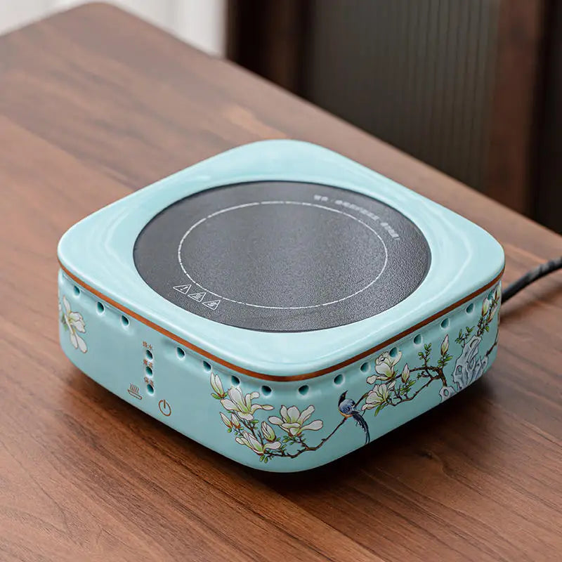 Light blue ceramic electric tea stove with floral print, round black heating plate, and touch control buttons.