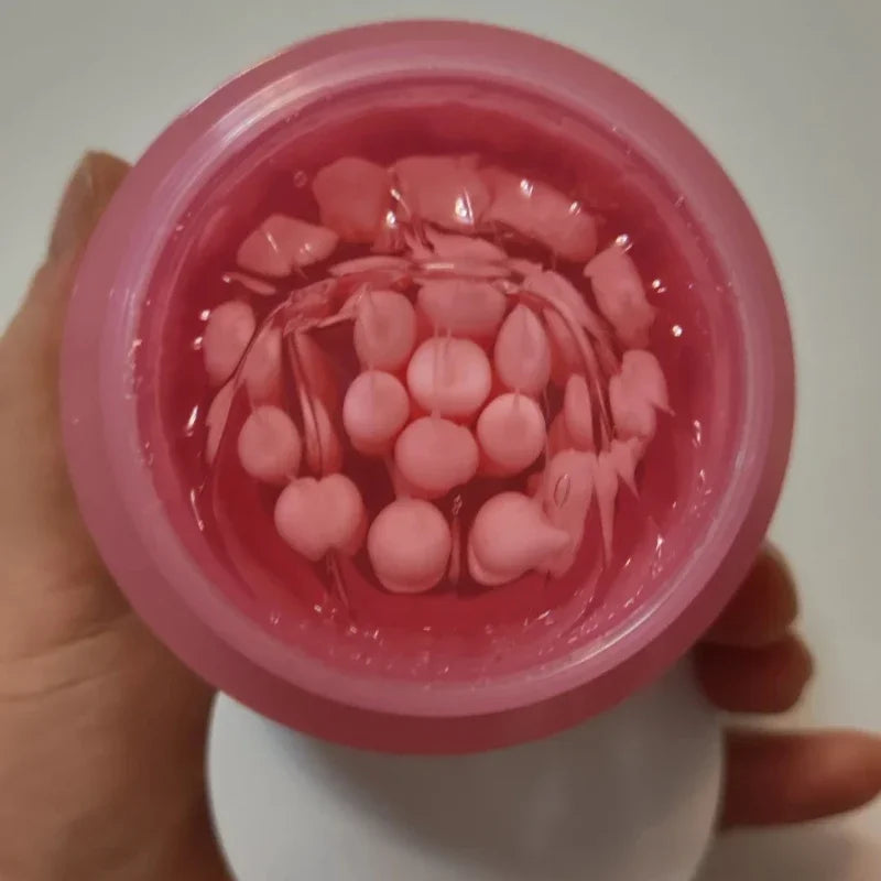Open jar of pink collagen cream featuring small, round, opaque pink capsules suspended in a clear, glossy gel.