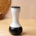 Electric Bian stone Gua Sha massager with a white hourglass-shaped handle and a smooth, rounded black massage head.