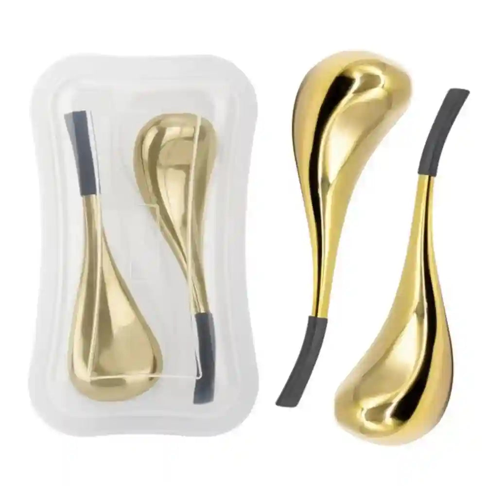 Two gold, teardrop-shaped facial massage globes with grey handles, shown in a clear plastic storage case and outside it.