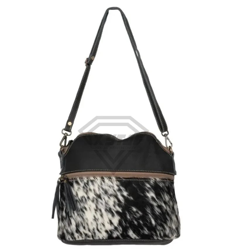 Black leather and cowhide hair-on crossbody shoulder bag with a zipper front pocket, luxury designer style.