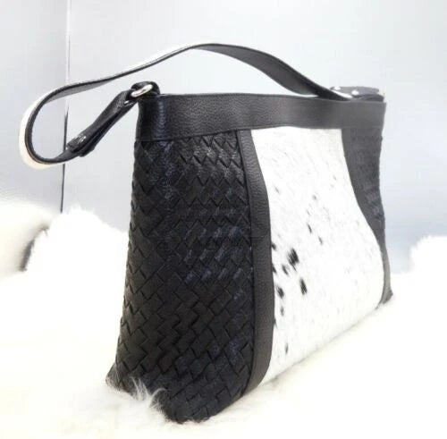 Designer handbag in black woven leather and white cowhide fur patchwork with a comfortable shoulder strap.