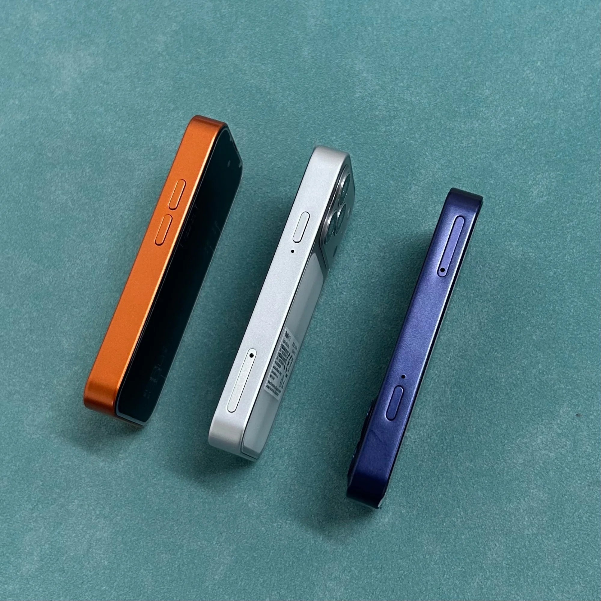 ONEMYTH A18 Pro 4G mini smartphones in orange, silver, and blue side profile view on green background.