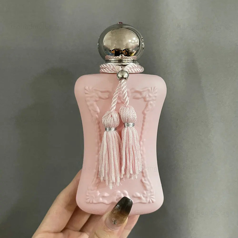 Luxury 75ml floral Eau de Parfum for women in a matte pink bottle with tassel detail and silver cap. Long-lasting scent.