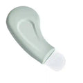 Sage green curved skincare tool for blackhead removal with a flat, rounded metal spatula tip on a white background.