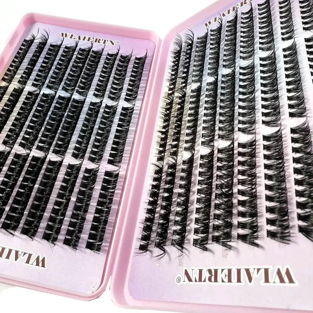 Large set of individual black synthetic eyelash clusters arranged on a pink plastic tray for cosmetic application.