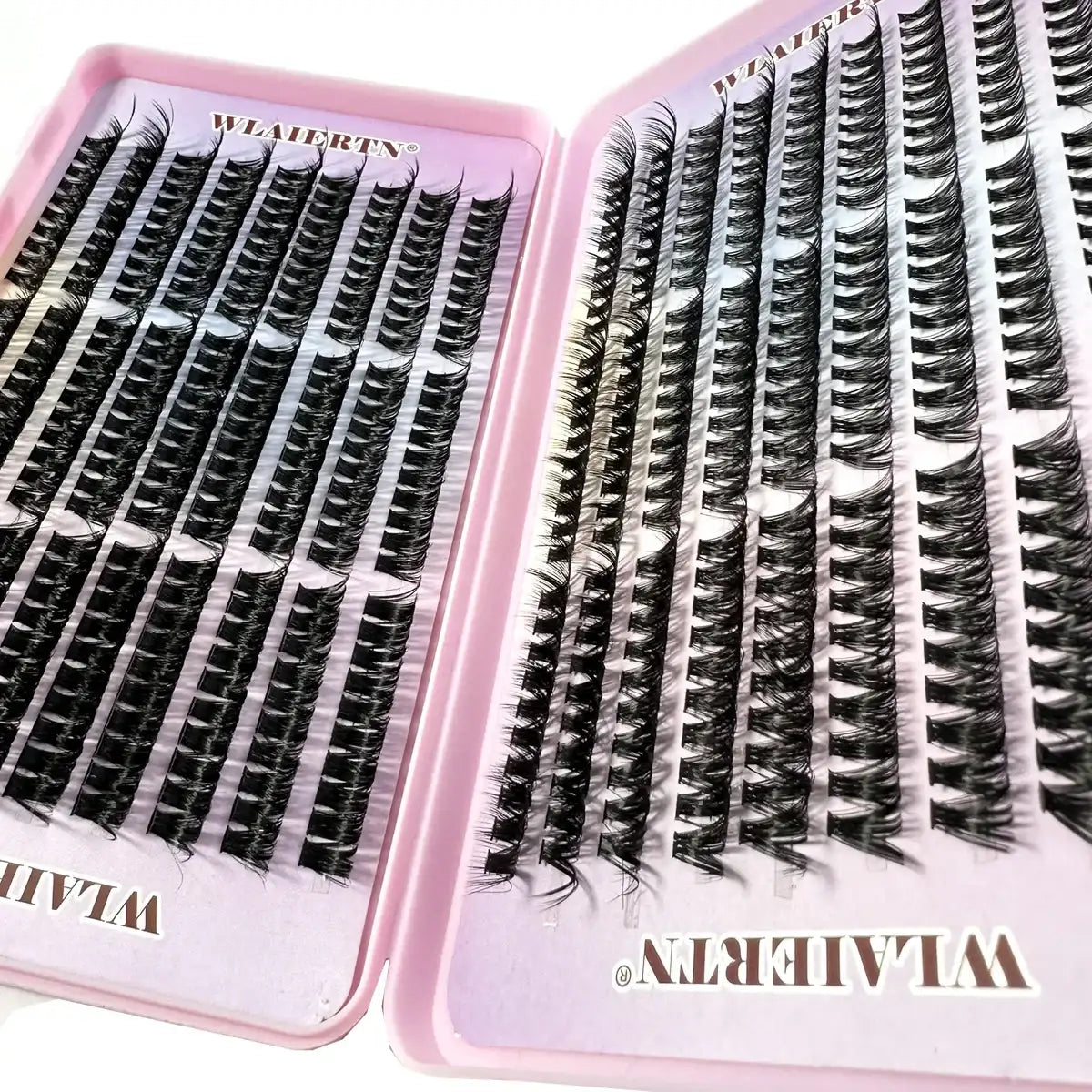 Individual black synthetic false eyelash clusters organized in rows within a pink plastic storage case.