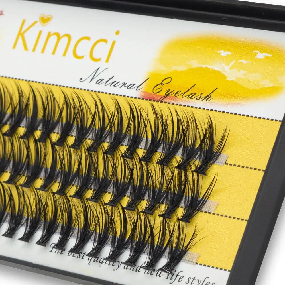 Tray of individual black, 3D volume mink eyelash extension clusters arranged on a yellow Kimcci branded background.