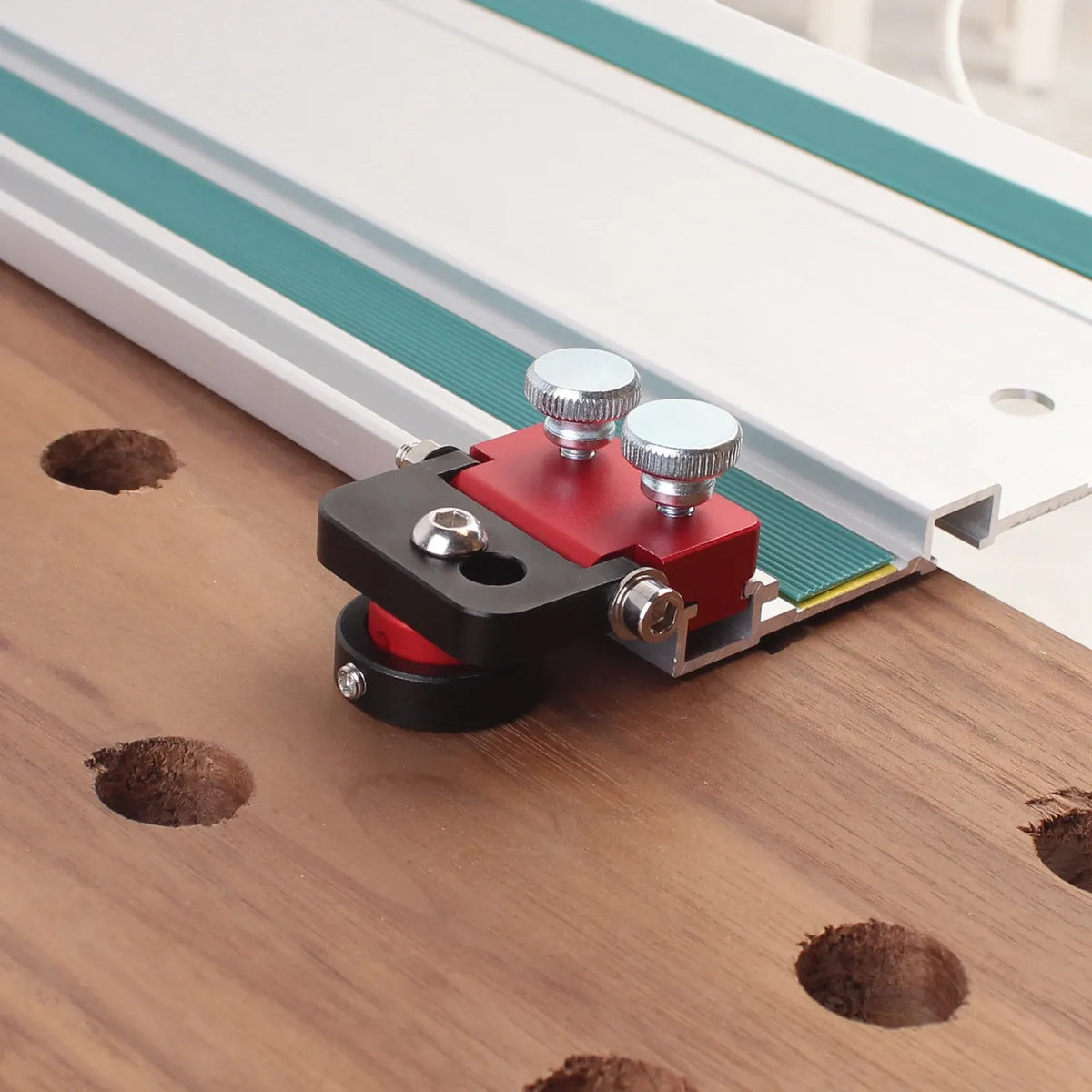 Track saw guide hinge dog clamp on wood, red plate, black base, two top bolts