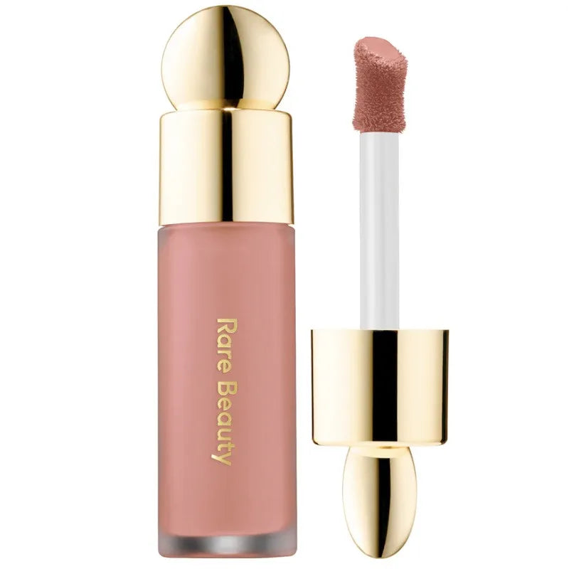 Rare Beauty matte liquid lipstick in a soft nude shade with a gold cap and precision applicator for a smooth finish.