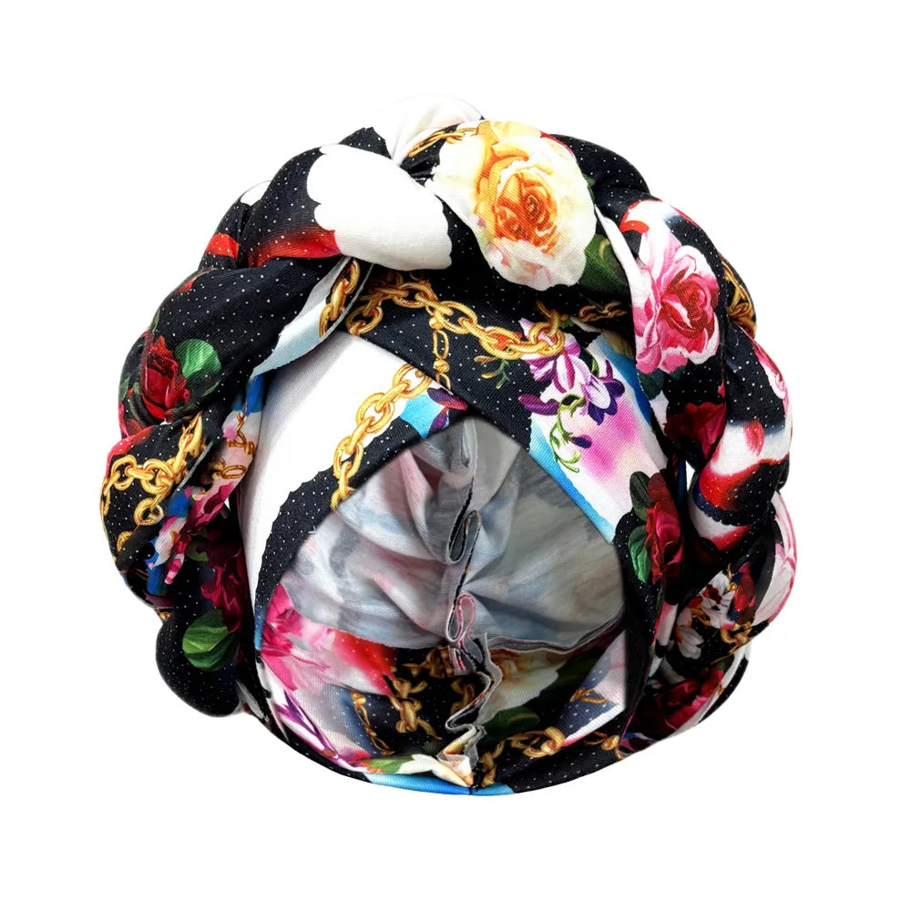 Tidesmit floral print turban featuring a black braided crown with gold chain accents and vibrant rose patterns.