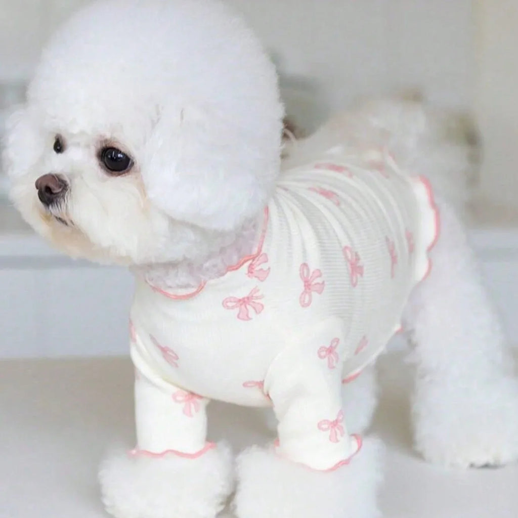 Bichon Frisé wearing a stretchy, breathable cream knit dog shirt with a pink bow tie print for comfortable pet fashion.