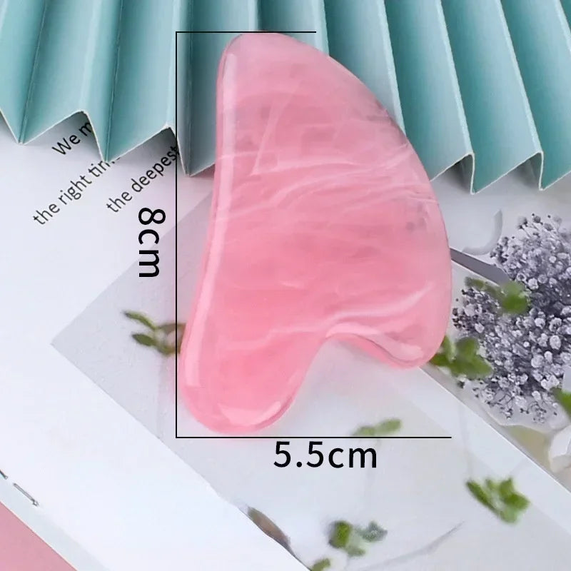 Heart-shaped pink resin gua sha facial massage tool with smooth, marbled texture, measuring 8cm by 5.5cm.