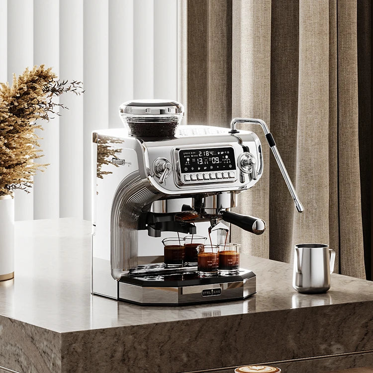 Stelang chrome espresso machine with integrated grinder, digital display, steam wand, and two glass coffee cups.