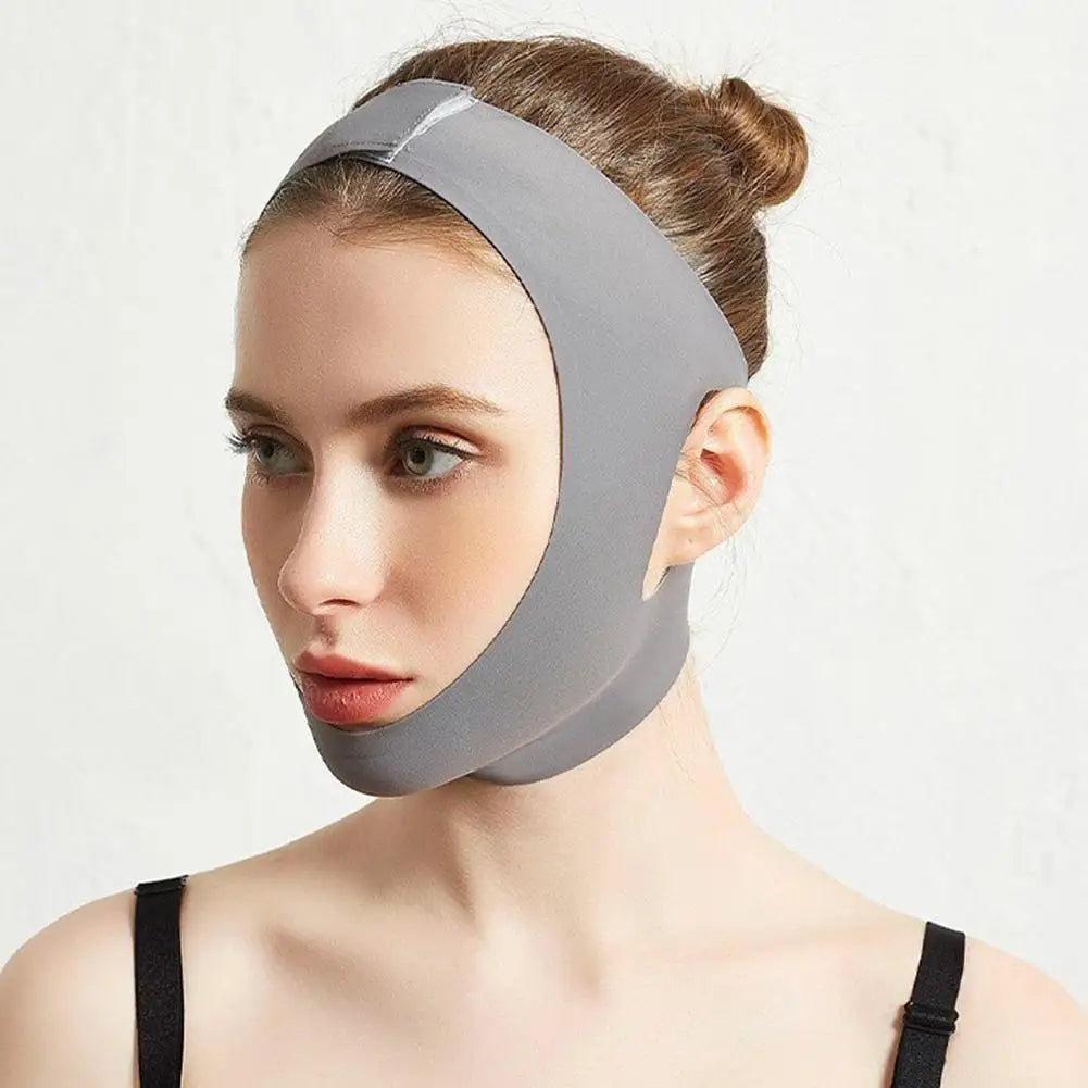A woman wears a grey, elastic V-line face slimming bandage strap that supports her chin and lifts her jawline.