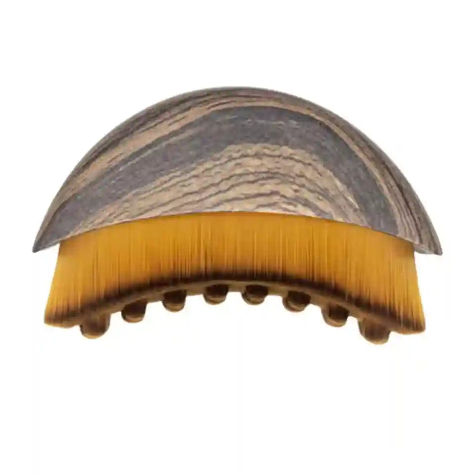 Curved facial brush with a grey wood-grain handle and soft, dense yellow-to-brown ombre bristles.