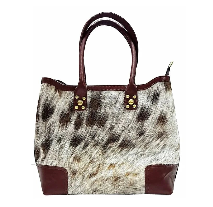 Handmade cowhide leather tote with brown leather trim, gold studs, and spacious design. Designer shoulder handbag.