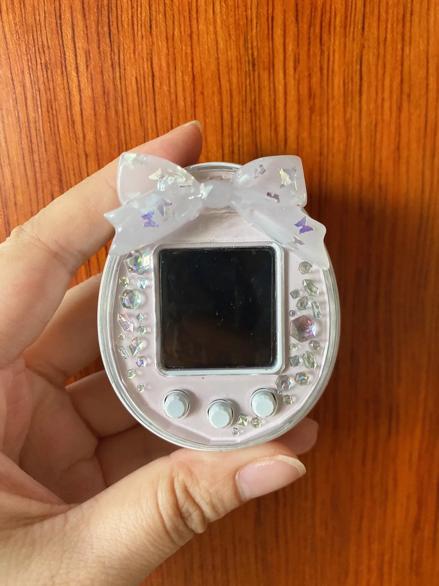 Pink Tamagotchi Uni hard shell case with butterfly bow and crystal accents for protective, stylish electronic pet decor.